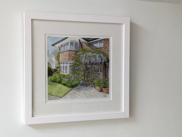 Framed watercolour house portrait hanging on a wall